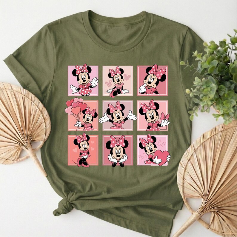 May include: Khaki green t-shirt with a grid of nine Minnie Mouse illustrations. Each square shows Minnie in different poses, wearing a pink polka-dot bow and dress. The background squares alternate between pink and peach tones.