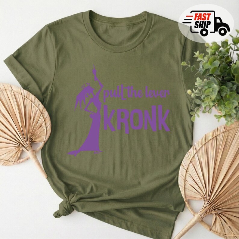 May include: Olive green t-shirt with a purple graphic of a character and the text "pull the lever KRONK". The shirt has short sleeves and a knotted hem. A "Fast Ship" logo is in the upper right corner.