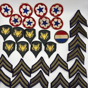 May include: A collection of military-style embroidered patches including circular red, white, and blue star emblems, black shield-shaped patches featuring gold eagle insignias, a circular red, white, and blue disc, and numerous chevron-shaped rank stripes.
