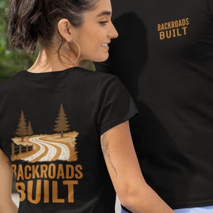 May include: Black t-shirts with the text "BACKROADS BUILT" in gold. One shirt has the text on the front, the other on the back, with a graphic of a winding road and trees. The shirts are worn by a man and a woman.