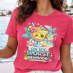 May include: A red t-shirt with the phrase "ON MY WORST BEHAVIOR" and a cartoon cocktail design. The design features a cocktail glass with a face, a small umbrella, and tropical elements. The shirt is being worn on a boat.