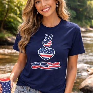 Woman wearing kayaking shirt creek floating design navy blue Bella Canvas 3001 t shirt standing in creek summer outdoor setting