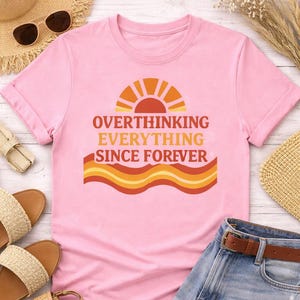Flat lay showing pink funny overthinking graphic shirt with summer outfit aesthetic unisex t shirt