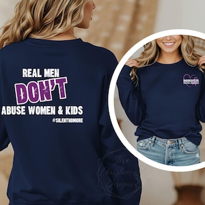 May include: A navy blue crewneck sweatshirt featuring white and purple text on the back that reads REAL MEN DON'T ABUSE WOMEN & KIDS #SILENTNOMORE. The front chest area displays a small purple heart graphic with the text DOMESTIC VIOLENCE AWARENESS.