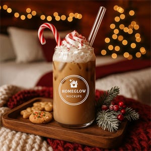 Puede incluir: Un vaso de café helado cubierto con crema batida, un bastón de caramelo y una pajita transparente. El vaso está sobre una bandeja de madera con galletas y ramitas verdes. El logotipo de Homeglow Mockups está en el vaso.