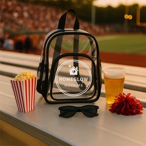 May include: A clear backpack with black trim, a popcorn container with red and white stripes, a plastic cup of beer, black sunglasses, and a red pom-pom are on a stadium bench. The backpack has the text "HOMEGLOW MOCKUPS".