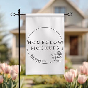 Peut inclure: Un drapeau de jardin blanc avec le texte "HOMEGLOW MOCKUPS" dans un cercle noir, avec les mots "Your design here" en dessous. Un support de drapeau de jardin en métal noir est au premier plan, avec une maison et des fleurs en arrière-plan.