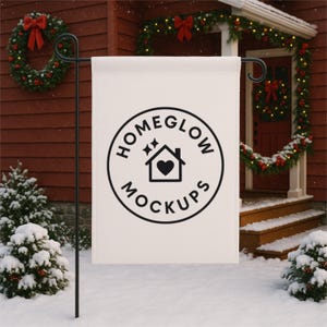 May include: A white garden flag with a black circular logo that reads "HOMEGLOW MOCKUPS" around a house icon with a heart. The flag is displayed on a black metal stand in a snowy outdoor setting, with Christmas decorations in the background.