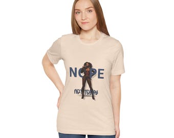 May include: Beige t-shirt with the word "NOPE" in blue block letters and the phrase "NOT TODAY" in a handwritten style. A graphic of a woman in a black outfit is between the words. The shirt is being worn by a person.