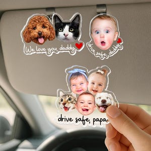 May include: Clear acrylic car visor ornaments featuring photos of a dog, cat, and baby with the text "We love you, daddy" and "drive safe, daddy". Another ornament has photos of babies, a cat, and a dog with the text "drive safe, papa".
