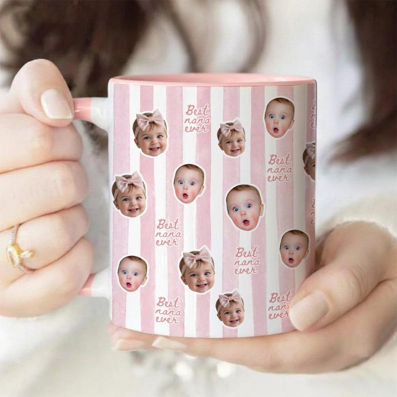 May include: A ceramic mug with a light pink and white vertical striped pattern. The mug features repeating circular photo cutouts of a baby wearing a pink bow, interspersed with the repeating cursive text "Best nana ever" in a light pink color.