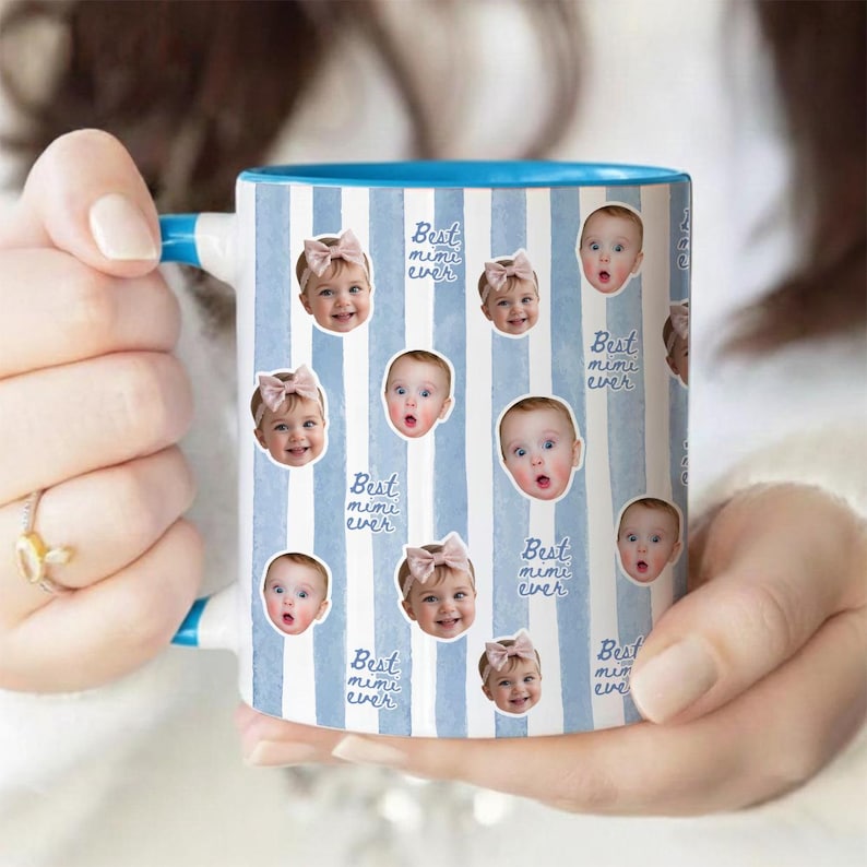 May include: A ceramic mug with a light blue and white vertical striped pattern. The mug features repeating circular portraits of a baby wearing a pink bow, interspersed with the handwritten-style blue text that reads Best mimi ever.