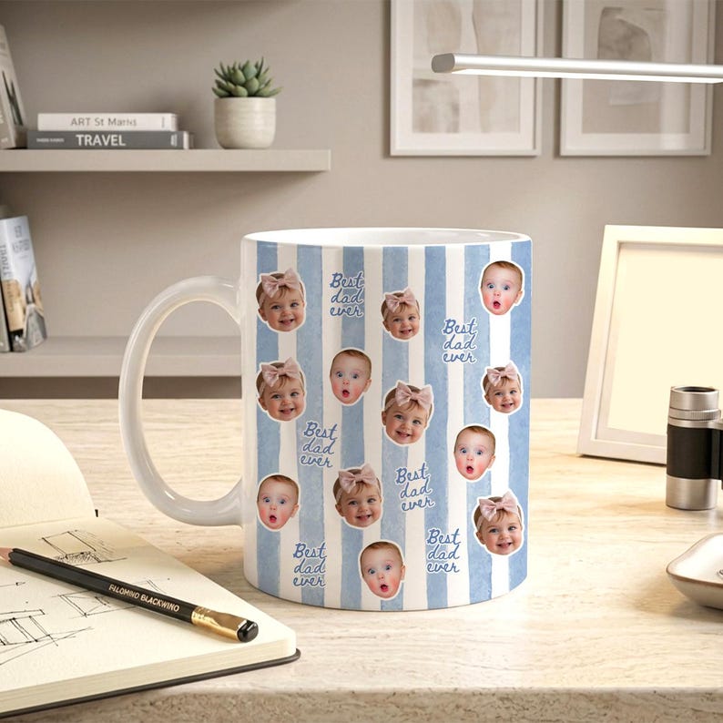 May include: A white ceramic mug featuring a repeating pattern of vertical light blue stripes, multiple small circular photographs of a baby wearing a pink bow, and the repeating blue cursive text that reads Best dad ever.