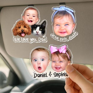 Puede incluir: Tres clips de acr&iacute;lico transparente para visera de coche con recortes de fotos personalizados. Uno muestra un beb&eacute;, un perro marr&oacute;n y un gato blanco y negro con el texto We love you, Dad. Otro muestra un beb&eacute; con una diadema azul y el texto drive safe, daddy. El tercero muestra dos beb&eacute;s y el texto Daniel & Sophia.