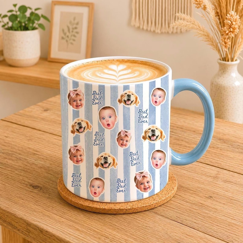 May include: A white ceramic mug with a light blue vertical striped pattern, featuring repeating photo prints of a baby and a golden retriever dog, interspersed with the blue text "Best Dad Ever" and a light blue handle filled with coffee.