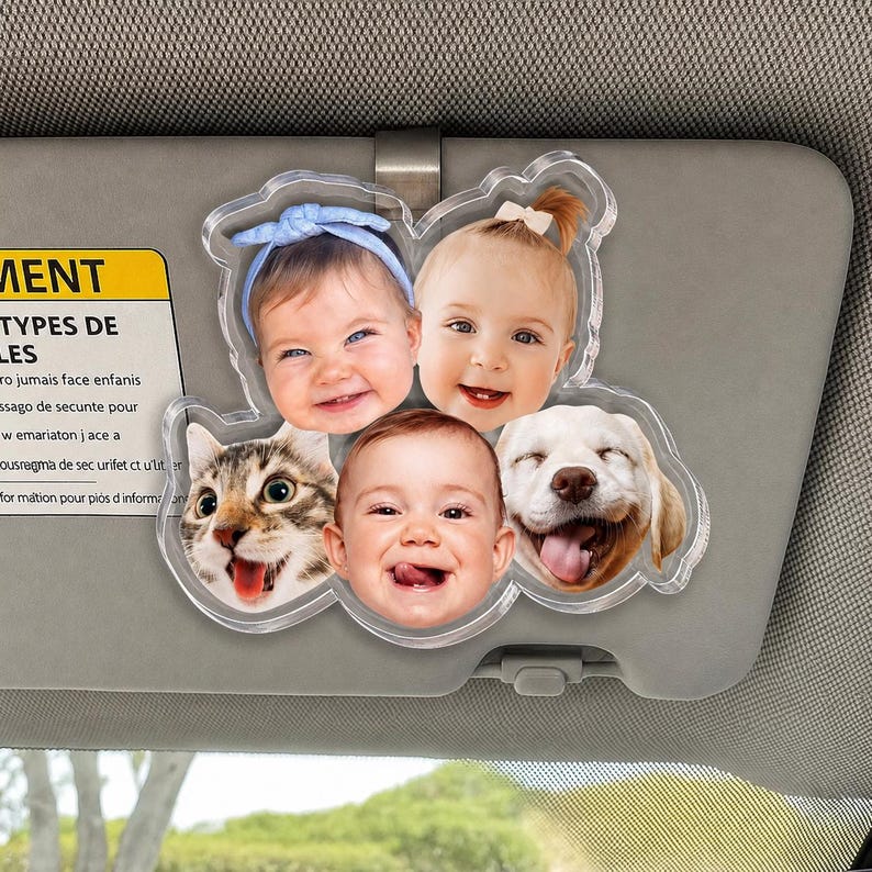 Puede incluir: Un clip de acr&iacute;lico transparente para visera de coche con cinco recortes fotogr&aacute;ficos circulares de tres beb&eacute;s y dos mascotas, incluyendo un gato atigrado y un perro de color claro. Los beb&eacute;s muestran expresiones faciales, uno lleva una diadema azul y otro un peque&ntilde;o lazo.