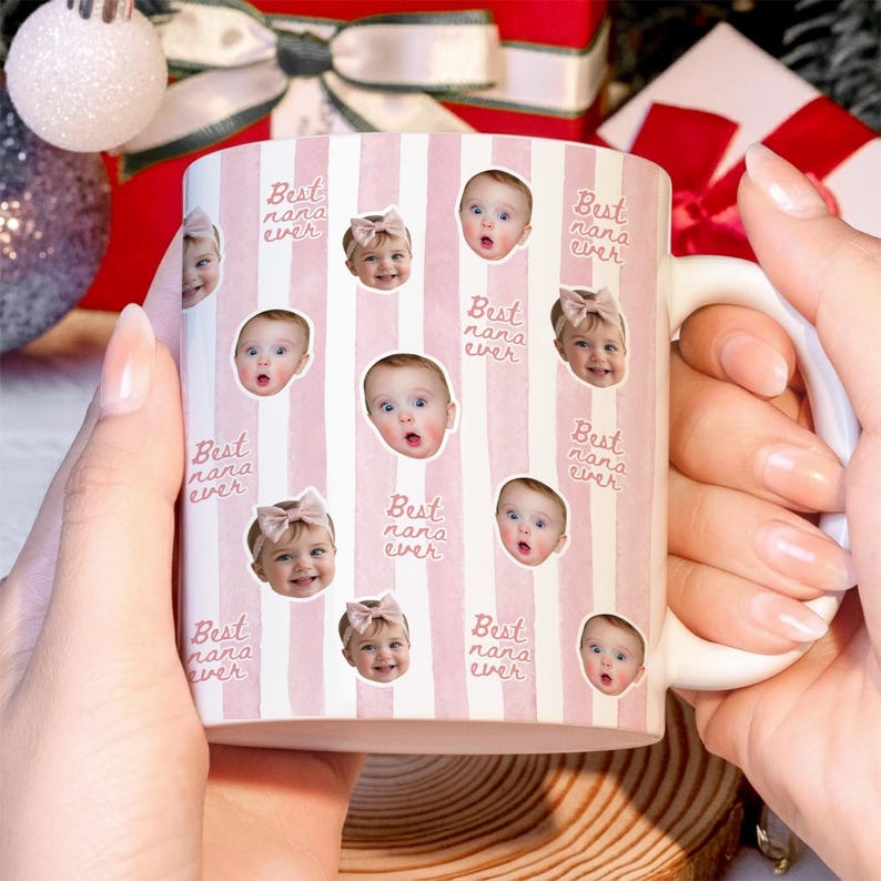 May include: A white ceramic mug featuring a repeating pattern of vertical light pink stripes and the text "Best nana ever" in a cursive script. The mug is decorated with multiple circular photo cutouts of a baby with various expressions.