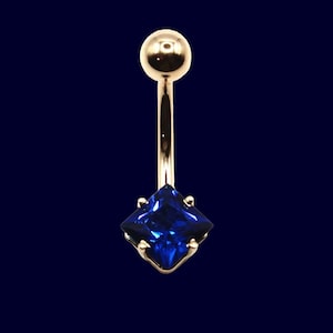 May include: A gold-coloured belly button ring featuring a square, deep blue gemstone. The ring has a small ball at the top and a curved bar leading to the gemstone setting. The gemstone is a vibrant, eye-catching blue.