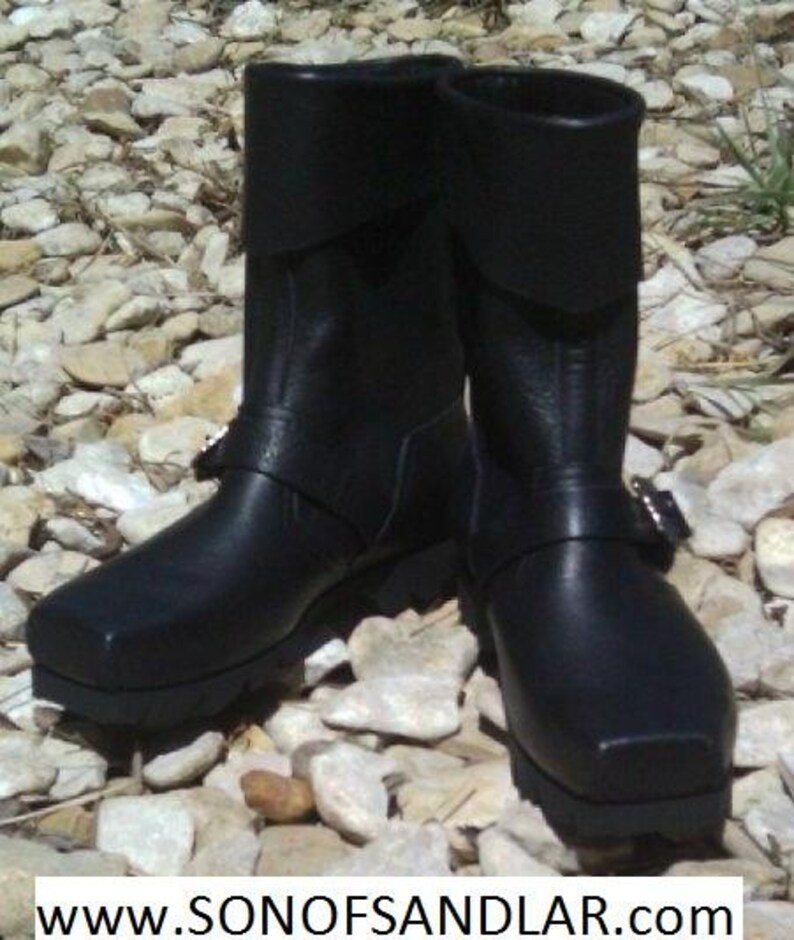 May include: A pair of black leather boots with buckles and a thick sole. The boots have a fold-over top and are made of a durable material.