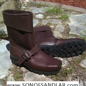 May include: A pair of brown leather boots with a buckle strap. The boots have a rugged sole and a fold-over cuff.