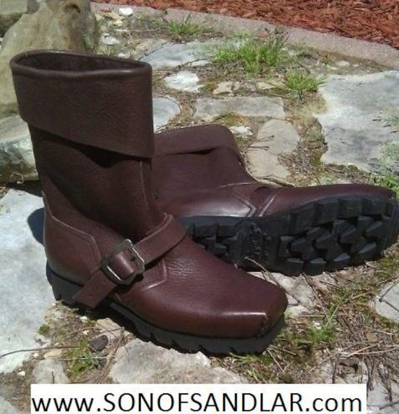 May include: A pair of brown leather boots with a buckle strap. The boots have a rugged sole and a fold-over cuff.