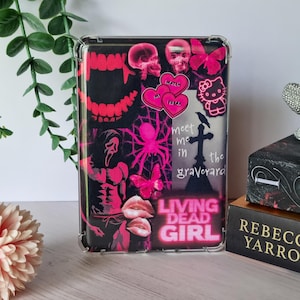 May include: A clear case featuring a black and pink design with skulls, butterflies, a spider, and the text "Living Dead Girl." The case also includes the text "Meet me in the graveyard" and a Hello Kitty graphic.
