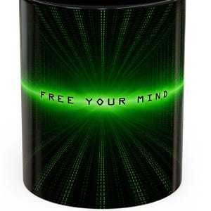 May include: A black ceramic mug featuring a digital matrix-style graphic with vertical green light streaks radiating from the center. The text "FREE YOUR MIND" is printed in a bold, dark font across the middle of the glowing green light effect.