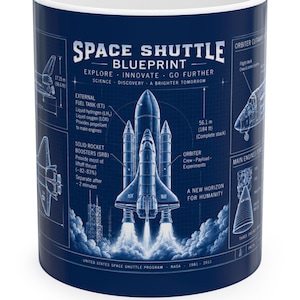 May include: A dark blue ceramic mug featuring a white technical blueprint of the Space Shuttle. The design includes detailed diagrams, labels for the external fuel tank and solid rocket boosters, and text reading Space Shuttle Blueprint.