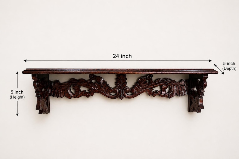 May include: A dark brown wooden wall shelf featuring intricate carved scrollwork and leaf patterns along the front support. The shelf measures 24 inches in width, 5 inches in height, and 5 inches in depth as indicated by the dimension labels.