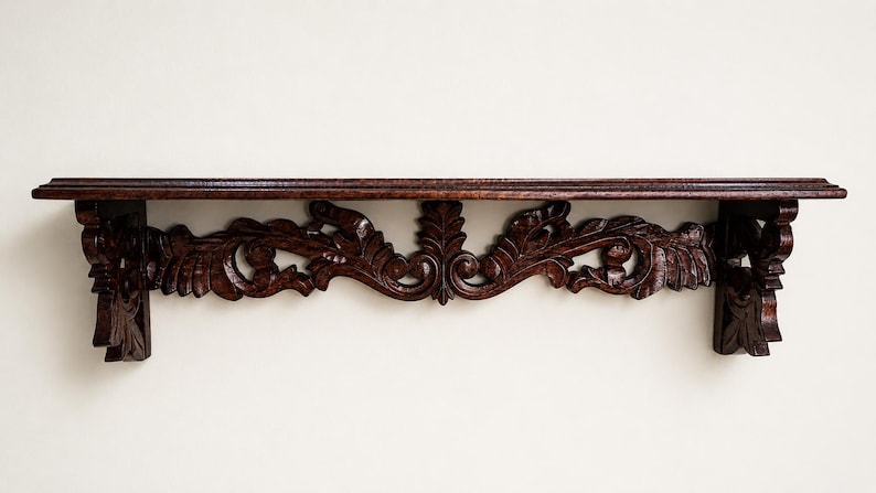 May include: A dark brown wooden wall shelf featuring an elongated rectangular top surface and a decorative apron underneath. The support brackets and the central section are intricately carved with detailed leaf and scroll patterns.