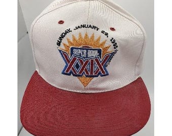 May include: A white and maroon baseball cap with the text "SUPER BOWL XXIX" embroidered on the front. The cap features a maroon bill and a button on top. The text "SUNDAY, JANUARY 29, 1995" is also embroidered on the cap.