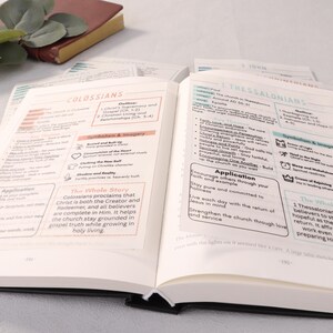 May include: Open Bible with notes on Colossians and 1 Thessalonians. The pages are filled with text, outlines, and highlighted sections in pink and blue. A small, closed book rests in the background.