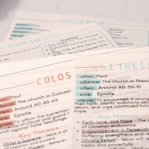 May include: Close-up of several study cards with text. The cards are white with pastel-colored text and headings. The cards include the names of books of the Bible, such as Romans, Colossians, and 1 Thessalonians, along with key themes and outlines.