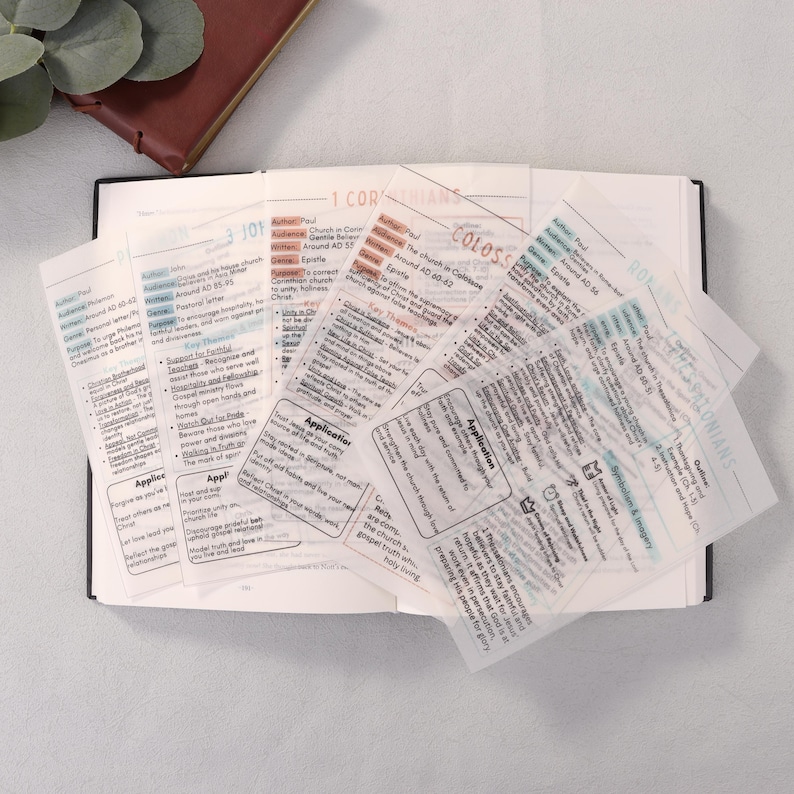 May include: Open book with several transparent sticky notes with text. The notes have titles like "1 Corinthians" and "Colossians". The text includes words like "Application" and "Epistle". A brown leather-bound book is visible.