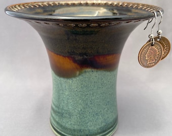 May include: A handcrafted ceramic vase with a flared rim, featuring a gradient of colors from dark brown to teal. Two coin earrings hang from the rim. The earrings are made from vintage Indian Head pennies.