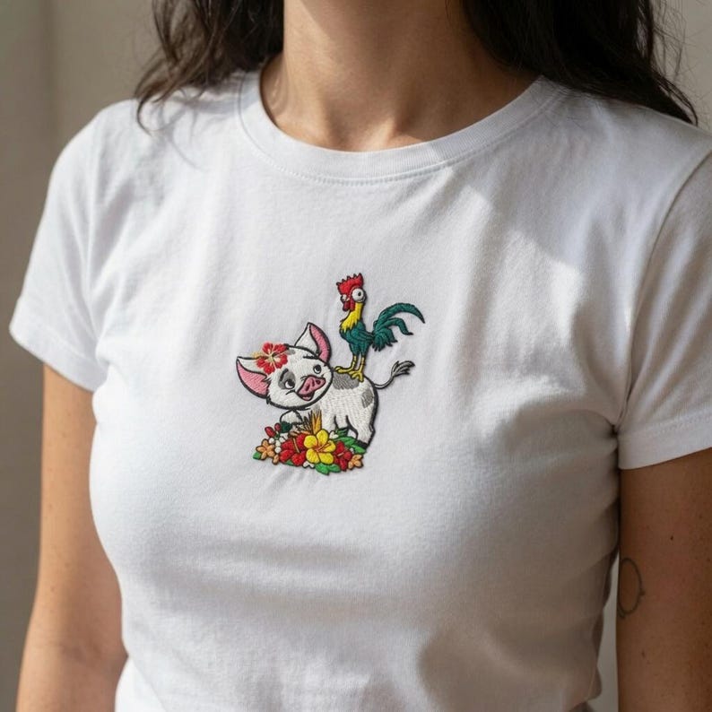 K&ouml;nnte beinhalten: Ein wei&szlig;es T-Shirt mit kurzen &Auml;rmeln und einer zentralen Stickerei, die ein kleines Schwein mit einer Blume auf dem Kopf und einen Hahn auf seinem R&uuml;cken zeigt, umgeben von bunten tropischen Blumen in Rot-, Gelb- und Gr&uuml;nt&ouml;nen.