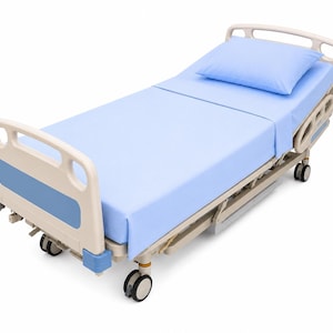 May include: A medical hospital bed with a beige frame and blue accents, featuring a light blue mattress and a matching pillow. The bed is equipped with side rails, a headboard, a footboard, and four swivel wheels for mobility on a white background.
