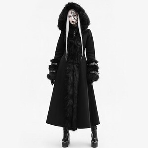 May include: A long black coat with a faux fur-lined hood and trim. The coat features fur cuffs and decorative buckles on the sleeves. The model is wearing black platform boots. The coat has a gothic or alternative fashion style.