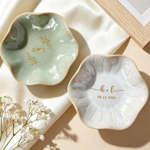 May include: Two scalloped ceramic trinket dishes, one in sage green and one in white. The green dish features gold text R heart S with leaf accents. The white dish displays gold text k + l and the date 08.22.2026 in a clean, elegant font.