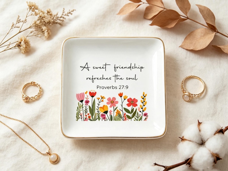 May include: A square white ceramic trinket dish with a gold-toned rim. The center features the black text A sweet friendship refreshes the soul Proverbs 27:9 above a colorful illustration of various wildflowers in shades of pink, red, and yellow.