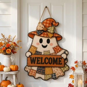 May include: A ghost-shaped wooden door sign featuring a patchwork pattern in orange, yellow, and green. The ghost wears a plaid witch hat with a fabric bow and holds a rectangular sign with the word WELCOME in bold black letters.