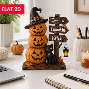 Op de afbeelding: Een decoratief tafelornament met drie gestapelde oranje pompoenen, waarvan de bovenste een zwarte heksenhoed draagt. Daarnaast staat een houten wegwijzer met de tekst Emma's Pumpkin Patch, een kleine hangende lantaarn en een zwarte kat.