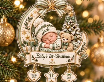 May include: A crescent-shaped Christmas ornament featuring a sleeping baby in a knit hat labeled Jack, a teddy bear, and gifts. A banner reads Baby's 1st Christmas 2026. Three charms hang below: a heart with Oct 20 2026, a star with footprints 8 lb 2 oz, and a cloud with 21 in.