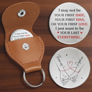 May include: A brown leather keychain case with a silver snap closure holds a round silver token. Two additional silver tokens are displayed, one with the text "I may not be your first date..." and the other with names and intertwined hands.
