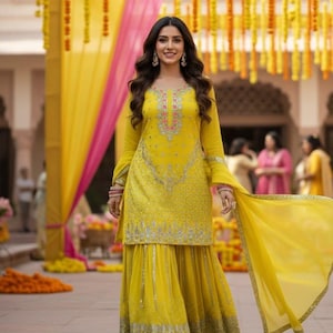 Pu&ograve; includere: Una donna in un vivace abito tradizionale indiano giallo, un salwar kameez, con ricami intricati e una dupatta abbinata. L'abito &egrave; adornato con dettagli argentati e rosa. Lo sfondo presenta decorazioni gialle e rosa.