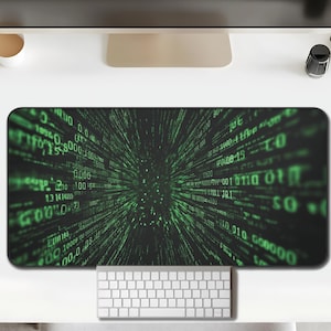 May include: A rectangular black mouse pad with a green digital rain design, a white keyboard, and a white mouse. The mouse pad features a matrix-style pattern of green numbers and symbols against a black background. The keyboard is positioned below the mouse pad.