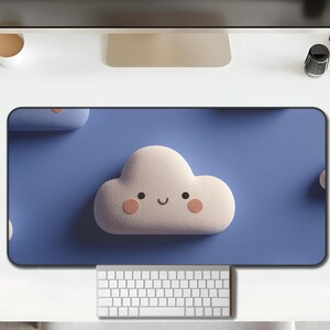 Puede incluir: Alfombrilla de escritorio azul con un diseño de nube blanca sonriente y mejillas rosas. La alfombrilla, de forma rectangular, está diseñada para teclado y ratón. Mide unos 70 cm de largo y añade un toque lúdico a cualquier espacio de trabajo.