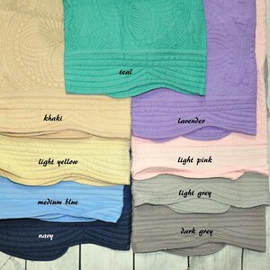 Puede incluir: Una colecci&oacute;n de diez muestras de tela acolchada con bordes festoneados y patrones circulares en relieve. Los colores est&aacute;n etiquetados como teal, khaki, lavender, light yellow, light pink, medium blue, light grey, navy y dark grey.