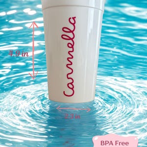 May include: A white plastic cup with the name Carmella printed in red script. The cup measures 3.1 inches in diameter at the top, 2.3 inches at the base, and 4.9 inches in height. A pink label indicates the cup is BPA free and holds 16 oz.