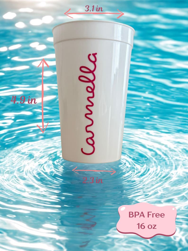May include: A white plastic cup with the name Carmella printed in red script. The cup measures 3.1 inches in diameter at the top, 2.3 inches at the base, and 4.9 inches in height. A pink label indicates the cup is BPA free and holds 16 oz.